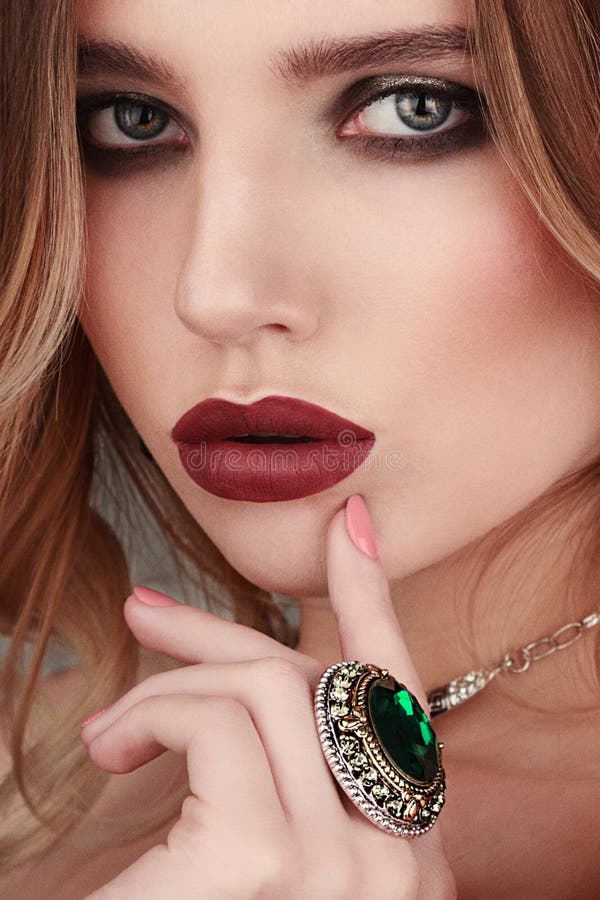 Closeup beauty portrait of young woman wearing ring with green g stock photo Closeup beauty portrait of young woman wearing ring with green g stock photo