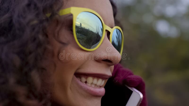 Closeup of biracial happy lady in sunglasses talking over phone, city reflection royalty free stock photo Closeup of biracial happy lady in sunglasses talking over phone, city reflection royalty free stock photo