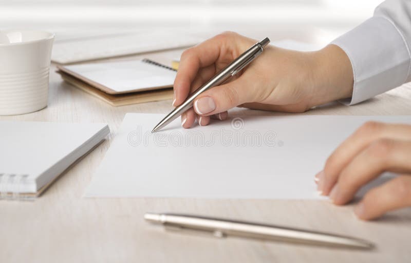 Primo piano di business womans scrittura a mano su carta alla scrivania.