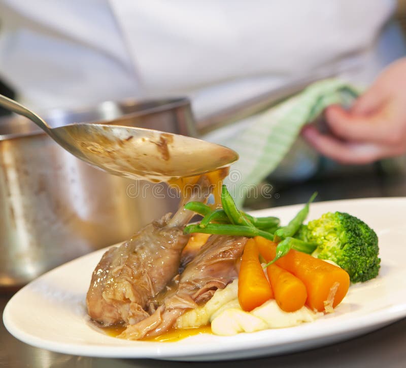 Closeup of chef pouring hot sauce on his dish