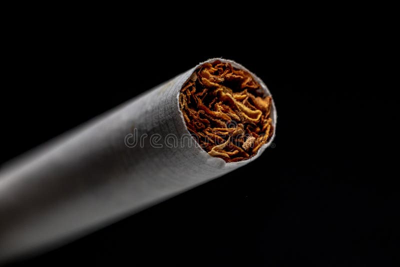 Closeup of a Cigarette Under the Lights Isolated on a Black Background