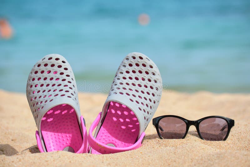 Closeup of Clogs Shoes and Black Protective Sunglasses on Sandy Beach ...