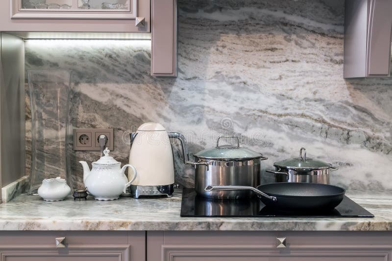 closeup of custom designed kitchen, with marble looking quartz countertop and backsplash. cream electric kettle with porcelain tea