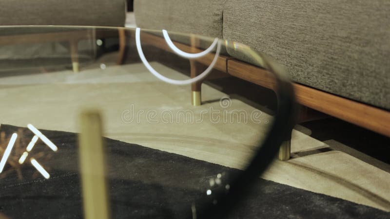 Closeup d'un canapé avec pieds en bois. Table basse design avec plateau en verre combiné à une belle base en bois pour clips vidéos