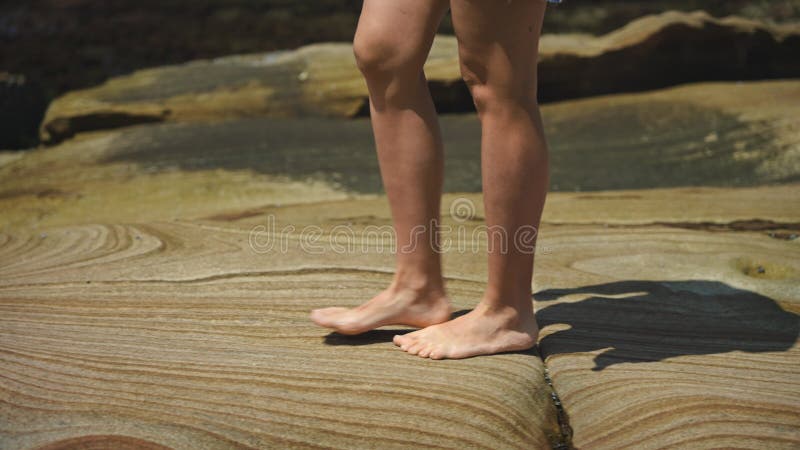 Closeup de picioare feminine goale subțiri care trec peste gresie frumoasă netedă cu modele naturale complicate stock footage