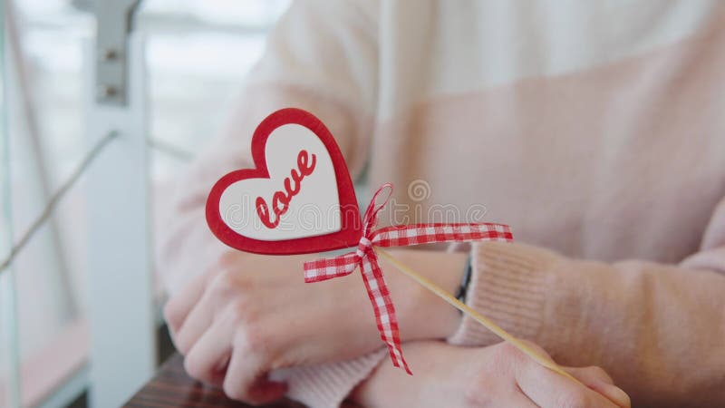 Closeup de valentines décor de jour entre les mains d'une fille en chandail rose assis à une table dans un café. le banque de vidéos