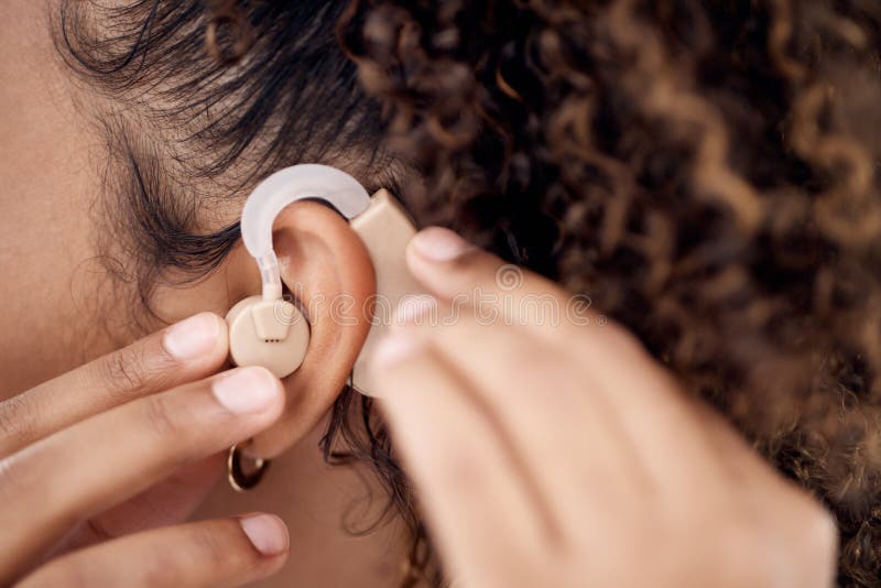 Closeup, deaf and woman with cochlear implant for hearing, audio and aid for disability or impairment. Sound, hands and. Girl fitting device to help with