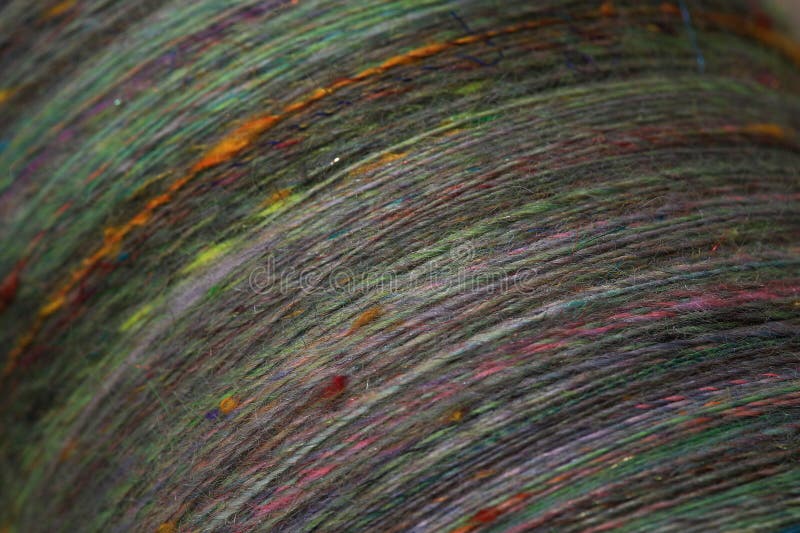 Closeup detail of colourful hand spun sheep wool merino fibres, rolled up in a yarn ball skein. Spun on a traditional spinning wheel. Closeup detail of colourful hand spun sheep wool merino fibres, rolled up in a yarn ball skein. Spun on a traditional spinning wheel