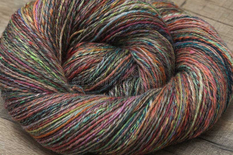 Closeup detail of colourful hand spun sheep wool merino fibres, rolled up in a yarn ball skein. Spun on a traditional spinning wheel