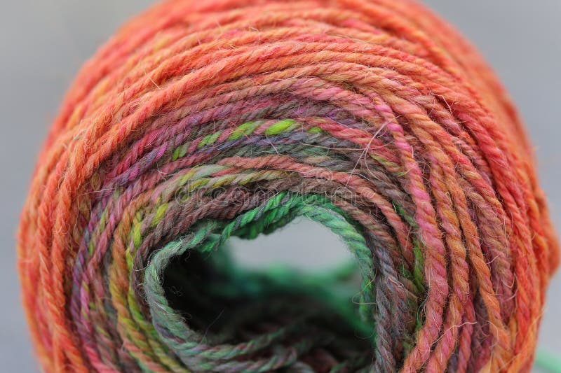 Closeup detail of colourful hand spun sheep wool merino fibres, rolled up in a yarn ball skein. Spun on a traditional spinning wheel