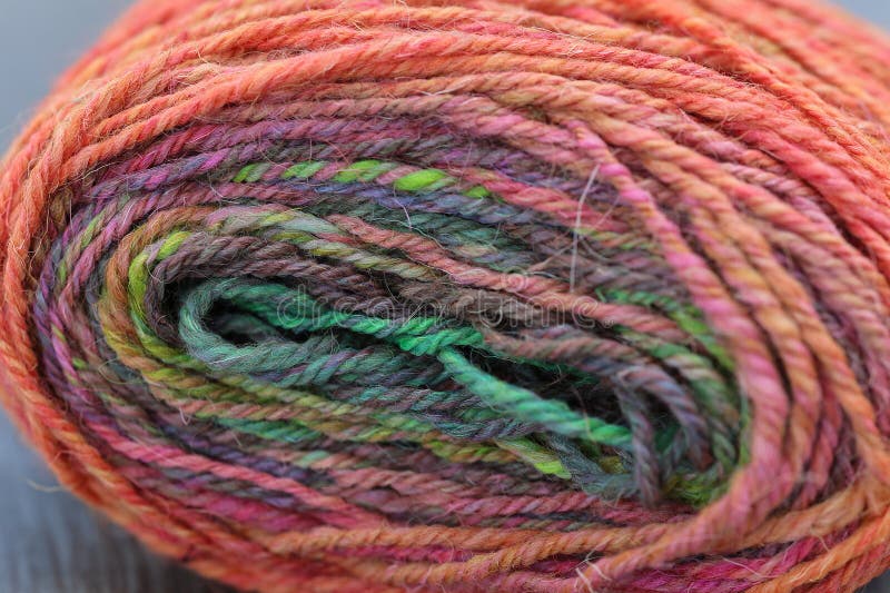 Closeup detail of colourful hand spun sheep wool merino fibres, rolled up in a yarn ball skein. Spun on a traditional spinning wheel