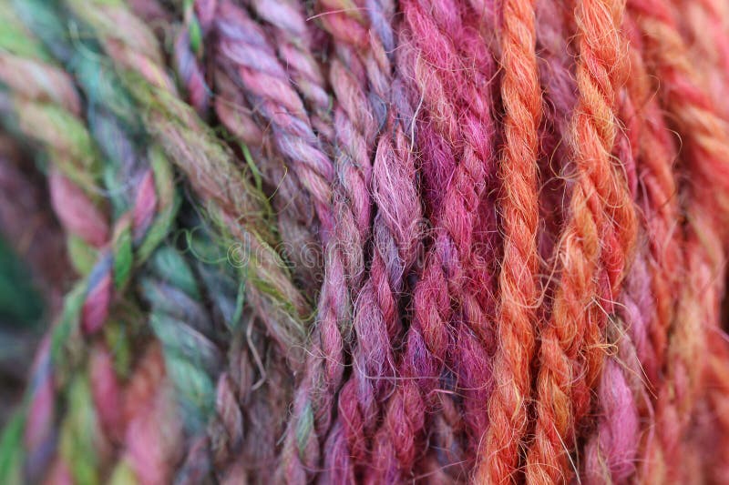 Closeup detail of colourful hand spun sheep wool merino fibres, rolled up in a yarn ball skein. Spun on a traditional spinning wheel