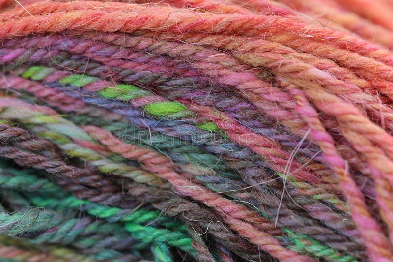 Closeup detail of colourful hand spun sheep wool merino fibres, rolled up in a yarn ball skein. Spun on a traditional spinning wheel