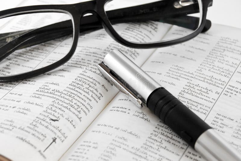 Closeup of dictionary and glasses with pen royalty free stock photos
