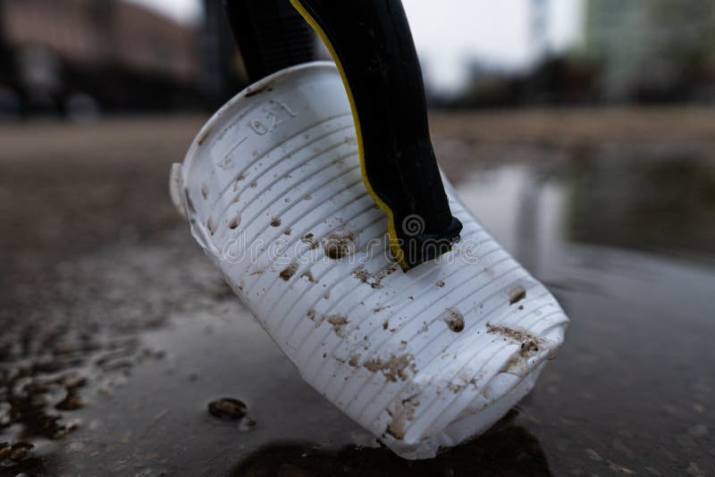 Closeup of a discarded disposable cup clipped between the jaws of a trash picker