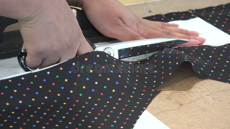 Seamstress cutting fabric with scissors stock footage