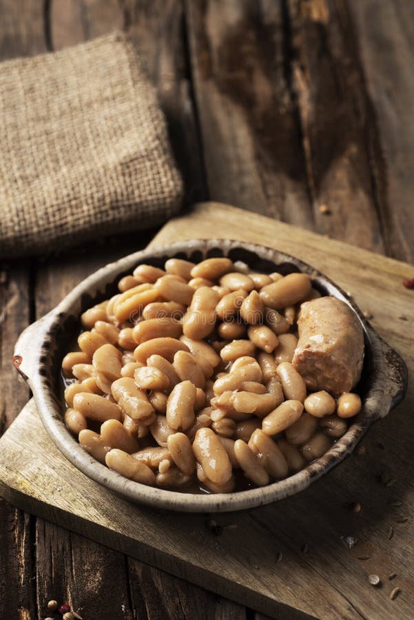 Closeup of an earthenware bowl with a cassoulet de Castelnaudary, a typical bean stew from Occitanie, in France, on a rustic wooden table. Closeup of an earthenware bowl with a cassoulet de Castelnaudary, a typical bean stew from Occitanie, in France, on a rustic wooden table