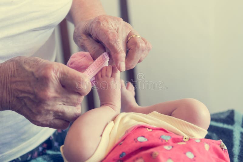 Closeup of elderly hands putting socks on newborn feet. stock photos Closeup of elderly hands putting socks on newborn feet. stock photos