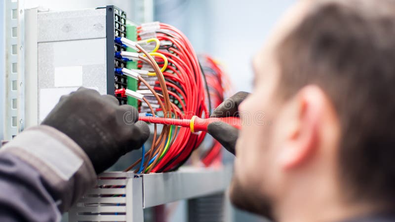 Closeup of electrician engineer works with electric cable wires stock photography