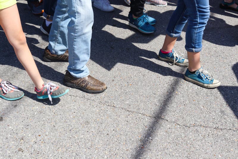 Closeup of feet and legs of People walking on cracked sidewalk with various shoes and pants