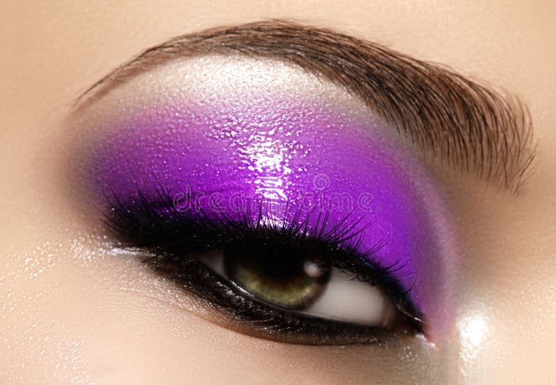 Closeup female eye with beautiful fashion bright make-up. Beautiful shiny blue eyeshadow, wet glitter, black eyeliner