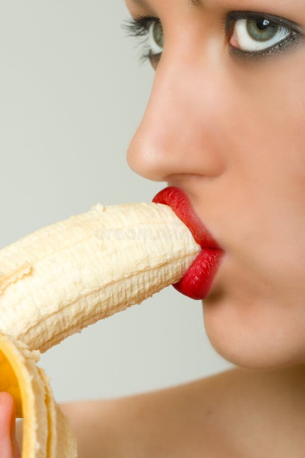 Closeup of female face biting a banana