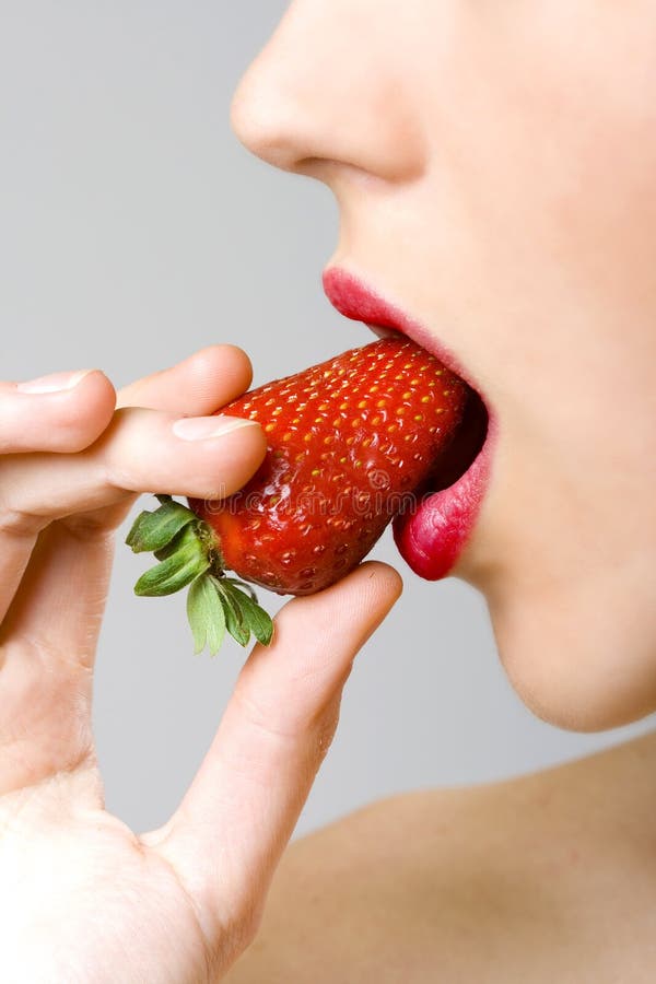 Closeup of female face biting a strawberry