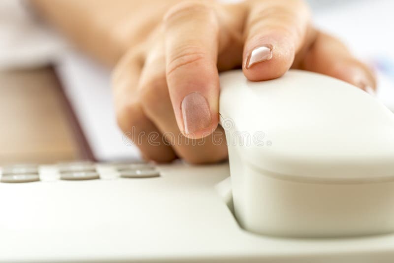 Closeup of female hand answering a call or hanging up holding handset of white landline telephone, shallow dof.