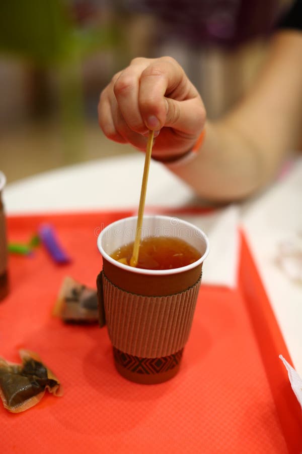Closeup of female hand stirring black tea in paper cup stock photos Closeup of female hand stirring black tea in paper cup stock photos