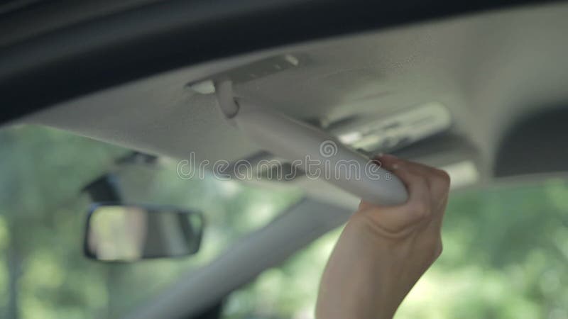 Closeup female hand taking car key from sun visor