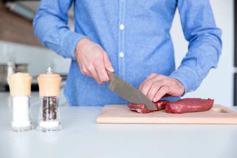 Closeup of fresh meat cutted by man with big knife royalty free stock photography