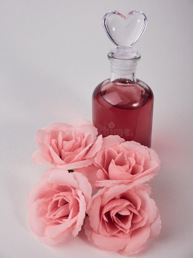 Closeup of a Glass Bottle of Perfume with Artificial Pink Roses on the