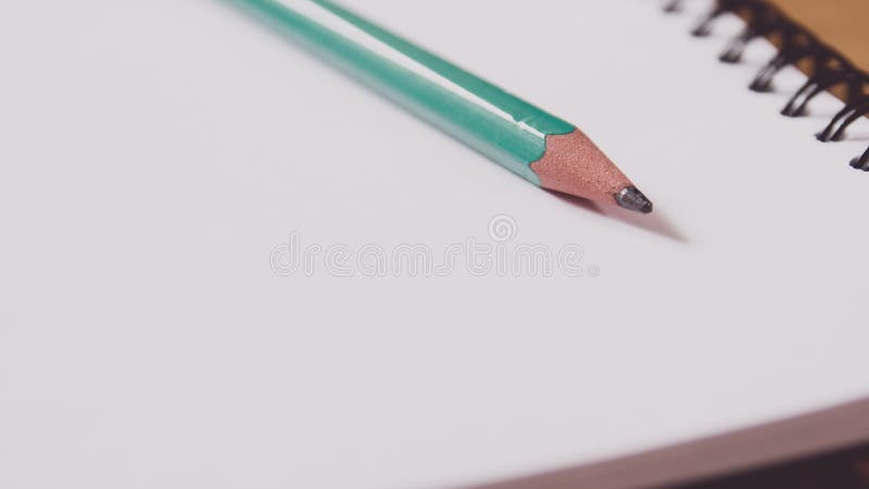 Closeup of a green pencil on a notebook. Notepad open on a blank page on the table stock images Closeup of a green pencil on a notebook. Notepad open on a blank page on the table stock images