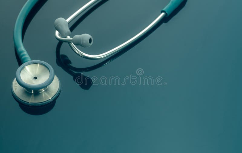 Closeup green stethoscope on doctor table or nurse desk. Health checkup or health insurance concept. Cardiology doctor equipment.