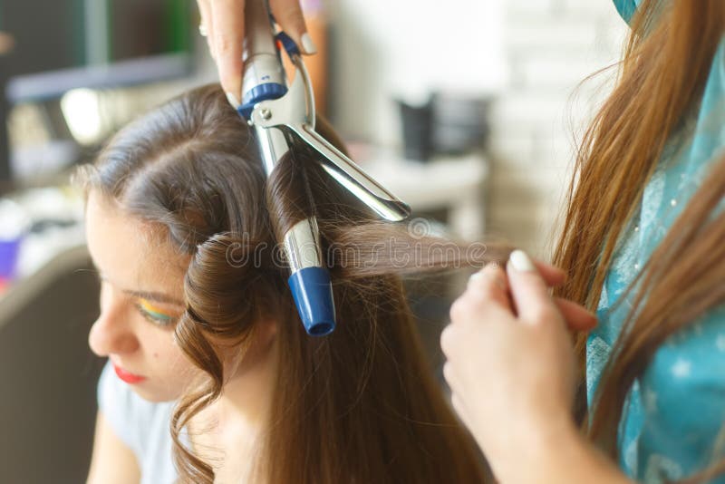 Closeup of hairdresser doing the styling for a festive evening of wedding hairstyles woman with long black hair royalty free stock image Closeup of hairdresser doing the styling for a festive evening of wedding hairstyles woman with long black hair royalty free stock image