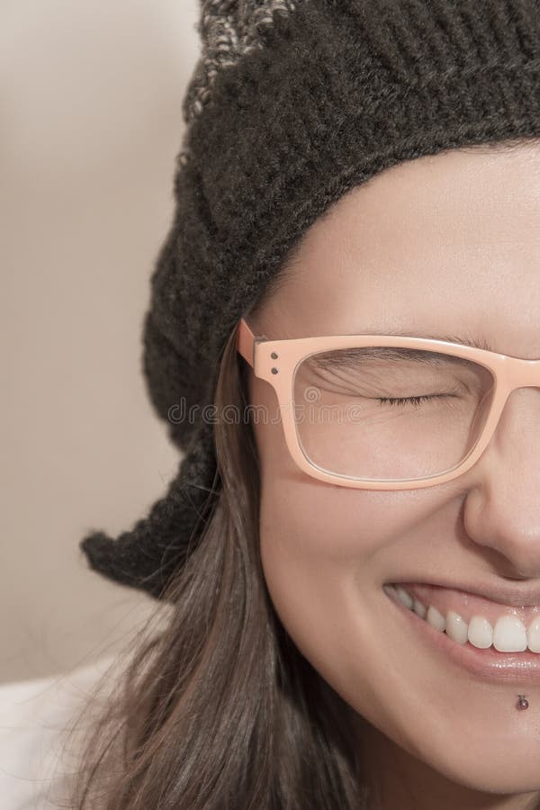 Closeup half face portrait of funny laughing woman with winter hat and summer glasses