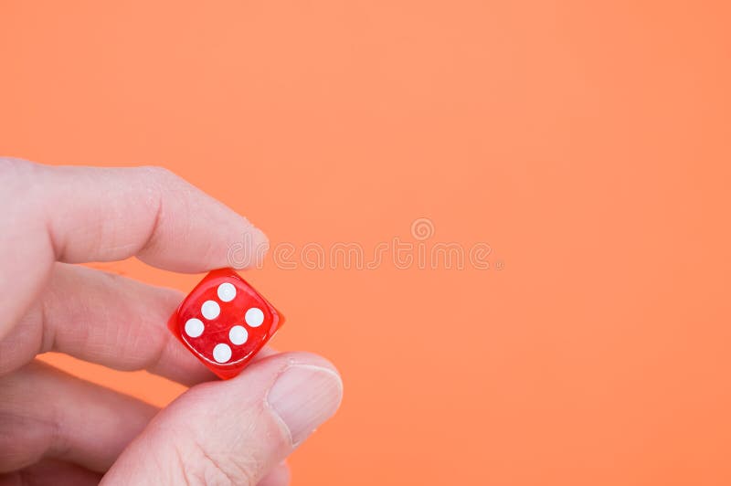 Closeup of a Hand Holding Red Rolling Dice on a Red Background Stock