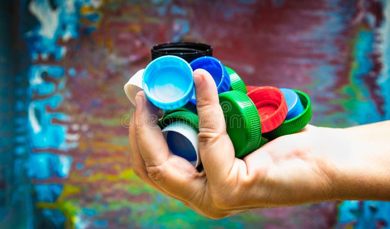 Closeup of a hand holdinmulti-colored plastic lids stock photo
