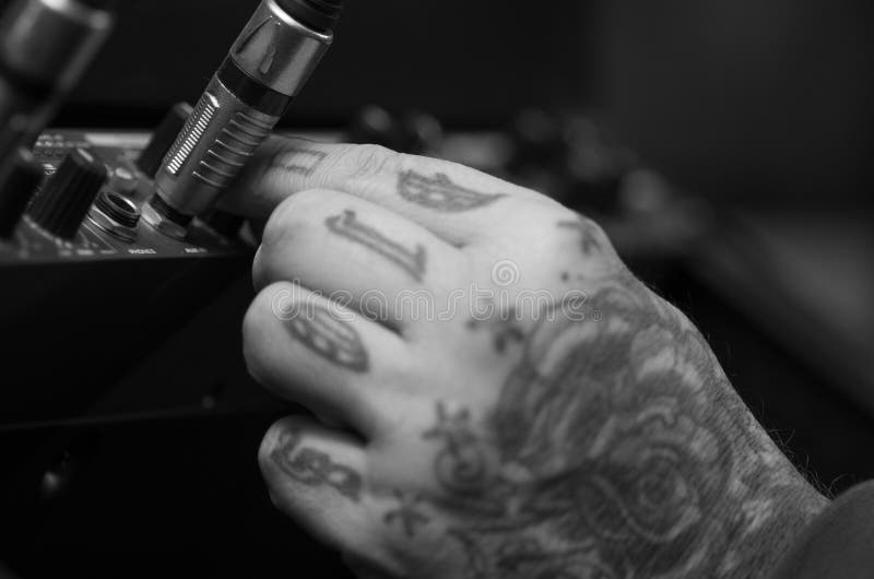 Closeup of hands covered with tattoos working on cable connection hardware audio box, studio equipment concept.