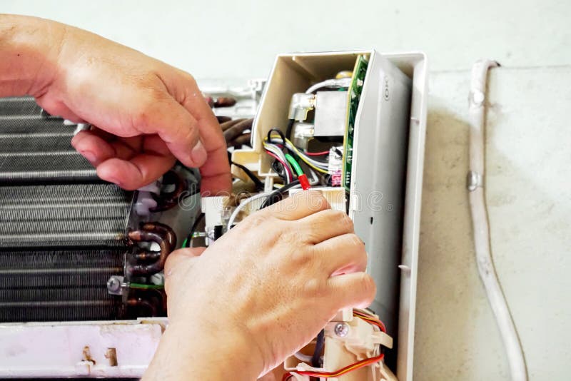 Closeup hands of electric repair technician fix an electronic board of home`s air conditioner