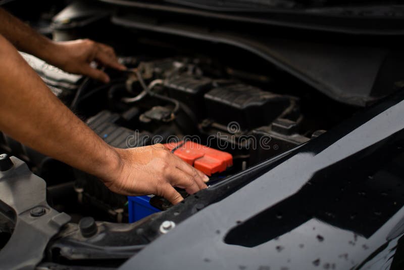 Closeup, the Hands of a Male Technician are Using a Tool To Replace the Car Battery, Parked at