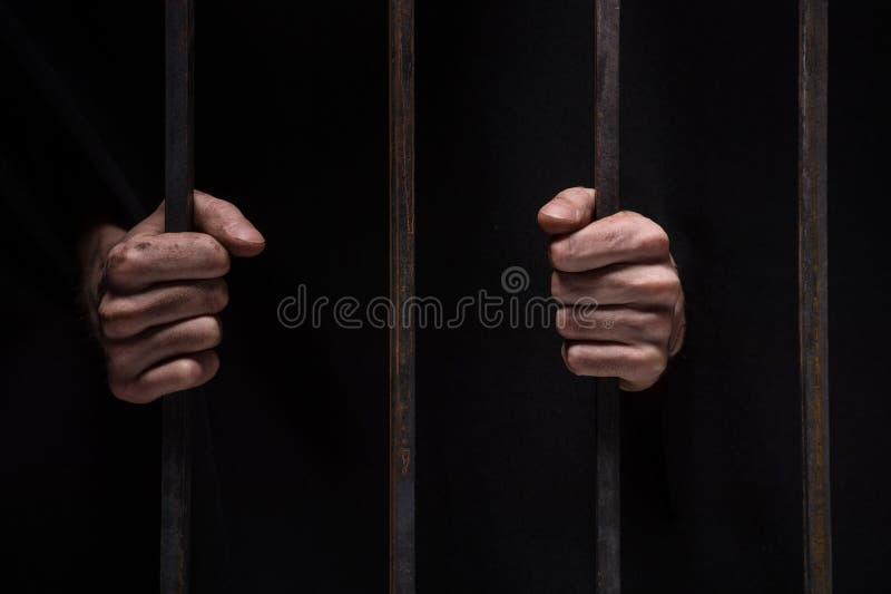 Closeup on hands of man sitting in jail.