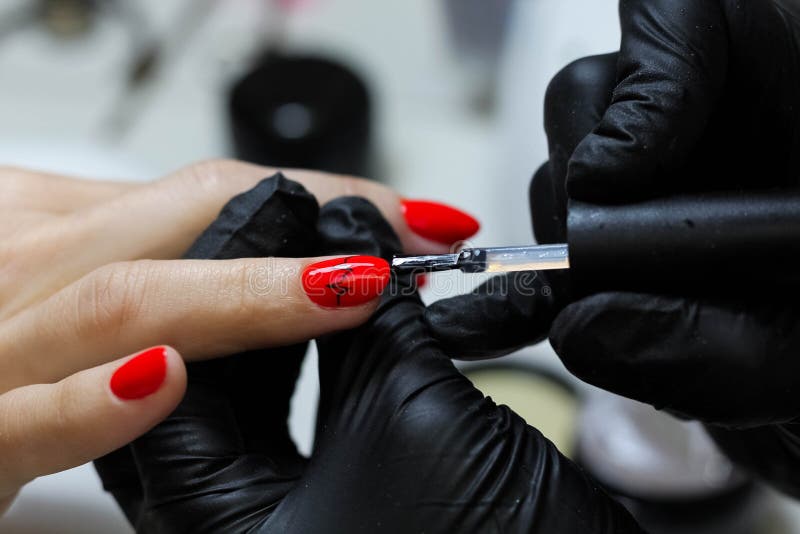 Manicure specialist in black gloves cares about hands nails. Manicurist paints nails with red nail polish stock images Manicure specialist in black gloves cares about hands nails. Manicurist paints nails with red nail polish stock images
