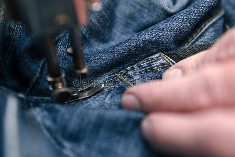 Closeup hands of Tailor man working on old sewing machine. jeans cloth fabric textile in shop, Tailoring, close up