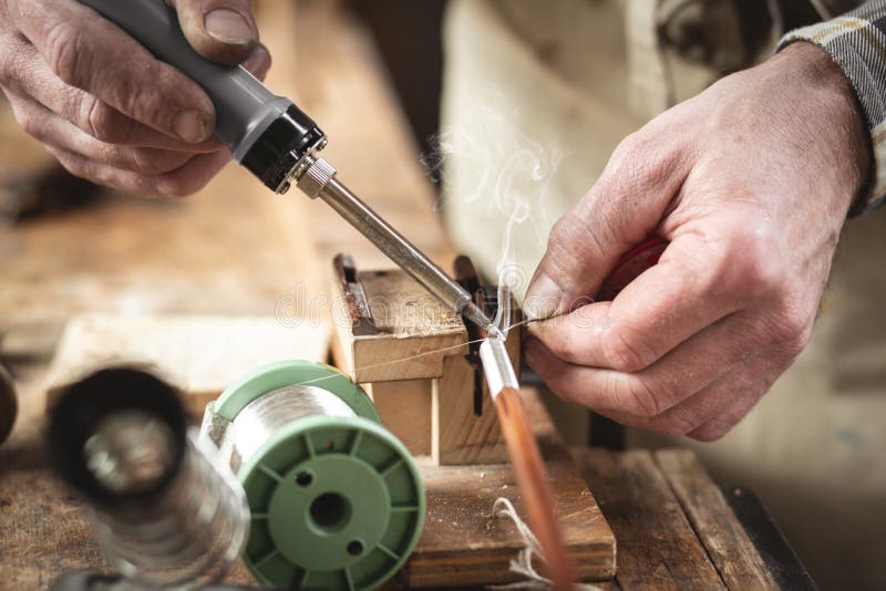 Applying a soldering iron on a rustic workbench royalty free stock images Applying a soldering iron on a rustic workbench royalty free stock images