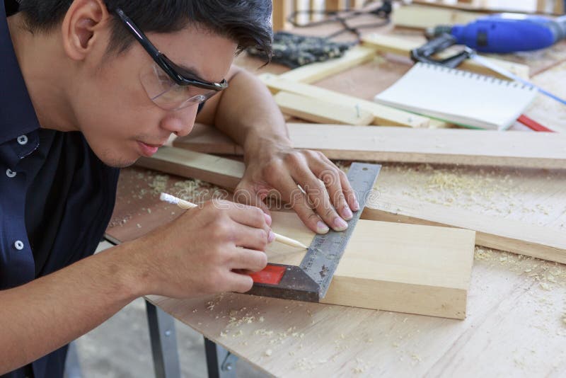 Closeup hands of young asian carpenter measuring on wooden job with try square