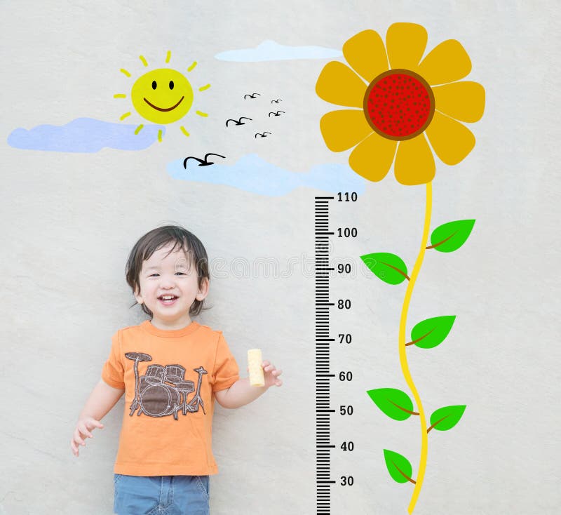 Closeup happy asian kid stand for measure height with cute cartoon sunflower at the marble stone wall textured background