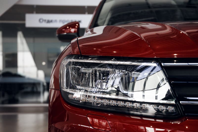 Closeup headlights of a modern red color car. Detail on the front light of a car. Modern and expensive car concept