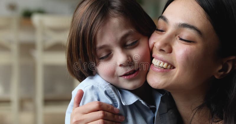 Closeup heureux jeune asiatique mère forte bouchées petit fils caucasien