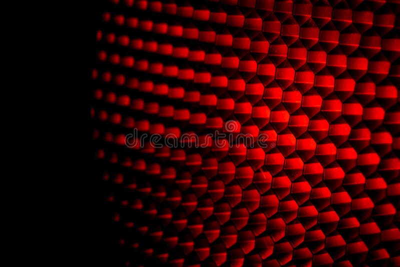 Closeup honeycomb grid texture with red light. Red and dark metal hexagon shaped pattern abstract background. Light modifier